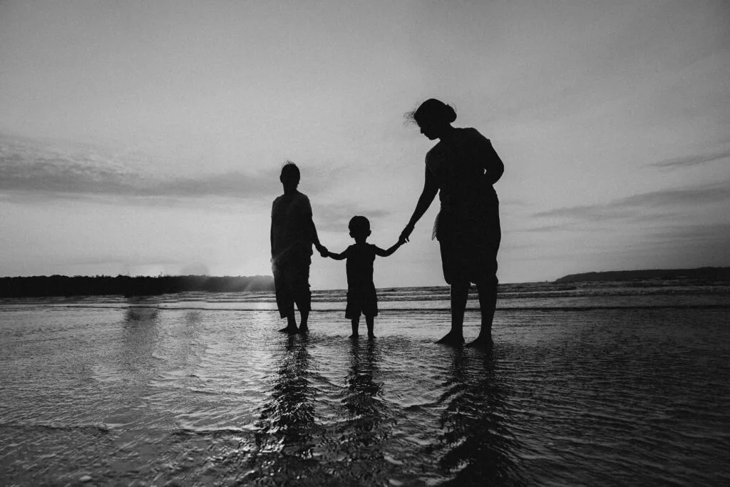 A family walking together on the beach, symbolizing balance, connection, and emotional wellbeing in a serene natural setting.