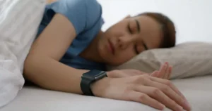 Person using a smartwatch to monitor sleep, showcasing how wellness gadgets can improve rest and relaxation, aligning with the focus of CalmTech-Life.com.